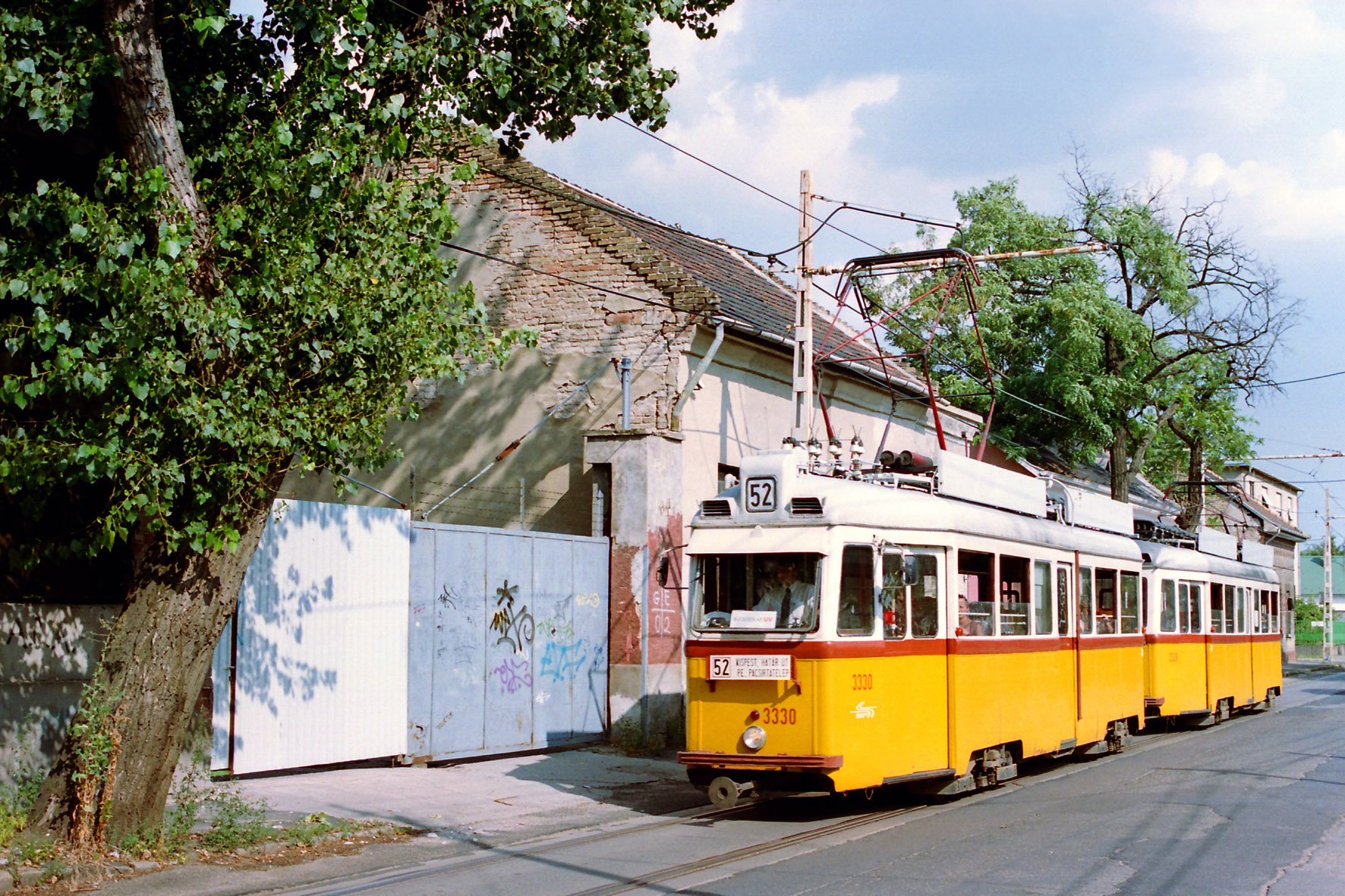 Délután több kocsin a szélvédő mögé egy „Búcsúzik az UV” feliratú matricát ragasztottak. Képünk a 3330-3329-es szerelvényről az Ady Endre utcában készült, a pesterzsébeti óriáshurokra meglehetősen jellemző környezetben. Alig héhány másodperccel később gyenge és rövid nyári zápor kezdte nedvesíteni az aszfaltot